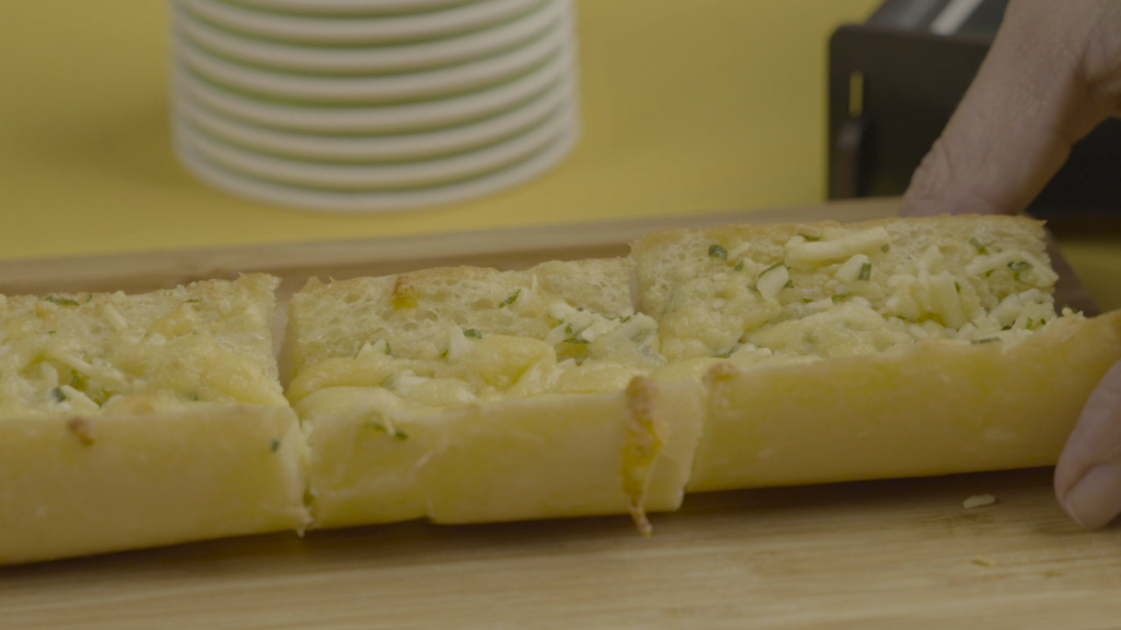 Pão de alho fatiado sob uma mesa de madeira